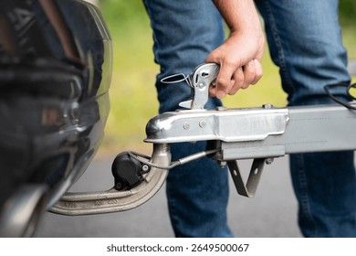 Nahaufnahme einer Hand, die eine Anhängerkupplung sicher am PKW verriegelt.